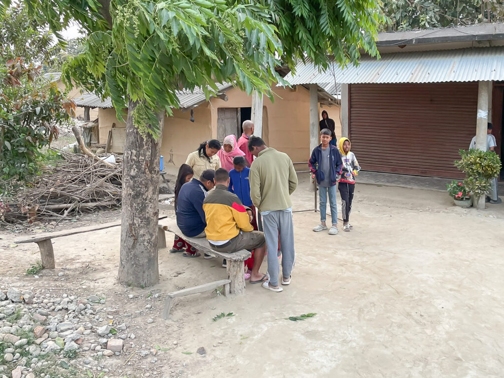 Community gathering in a courtyard next to houses in Bardiya, Nepal