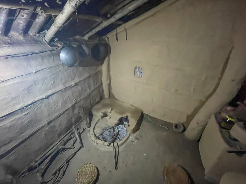 Traditional mud-walled kitchen with open hearth and cooking pots in Bardiya, Nepal.