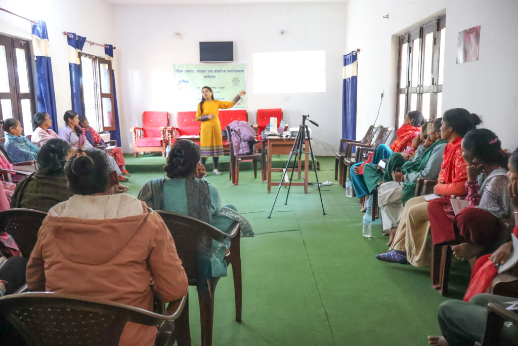 Wide view of a GEDSI training session in Bardiya, Nepal, with a facilitator presenting to participants seated on both sides of the room.