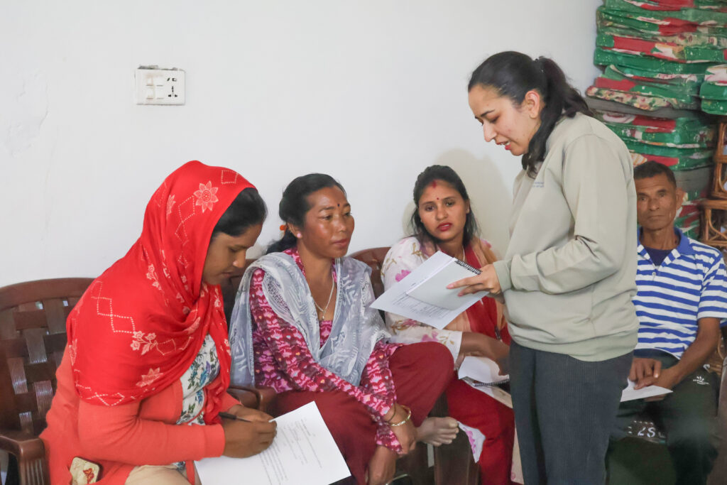 Facilitator speaking with workshop participants seated indoors in Bardiya, Nepal, during a Project GANESHA GEDSI training session.