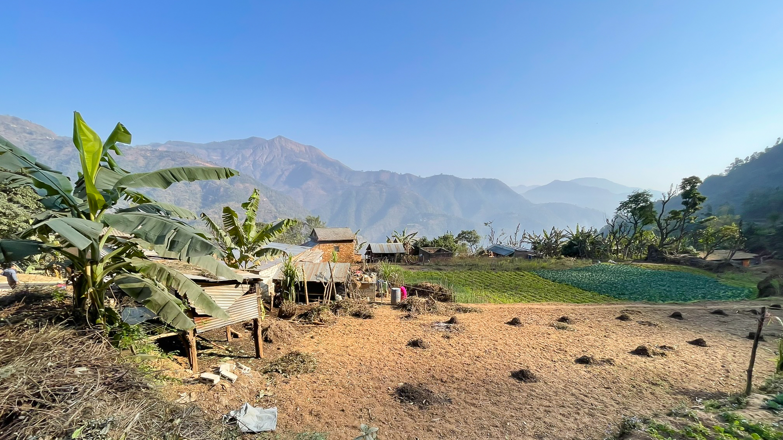 Rural homes and agricultural land in mountainous Nepal, representing a real-world battery delivery environment.