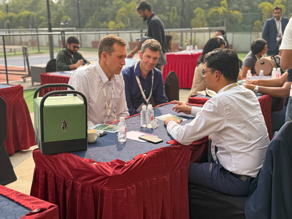 Philip and David sitting at an outdoor table meeting with potential investors at Sankalp Bharat in India