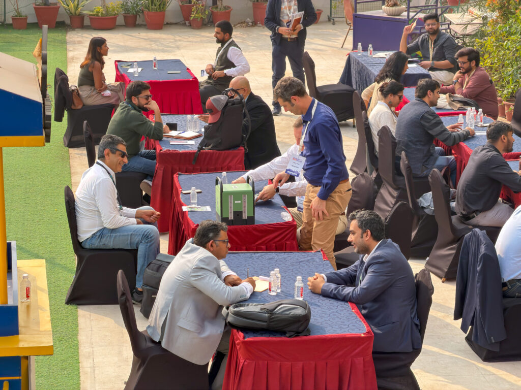 Philip and David sitting at an outdoor table meeting with potential investors at Sankalp Bharat in India