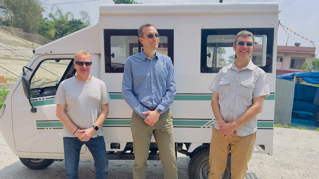 Paul Kerby, David Tetlow and Philip Tyler standing in front of an EV Rickshaw in Kathmandu, Nepal