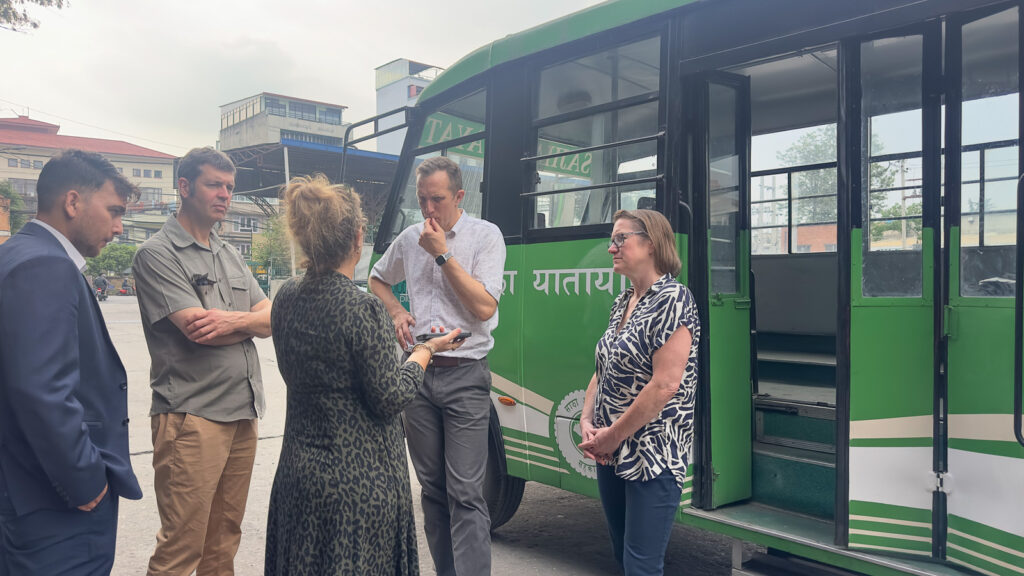 sajha-yatayat-meeting-nepal outside with their green bus behind three men and two women in coversation